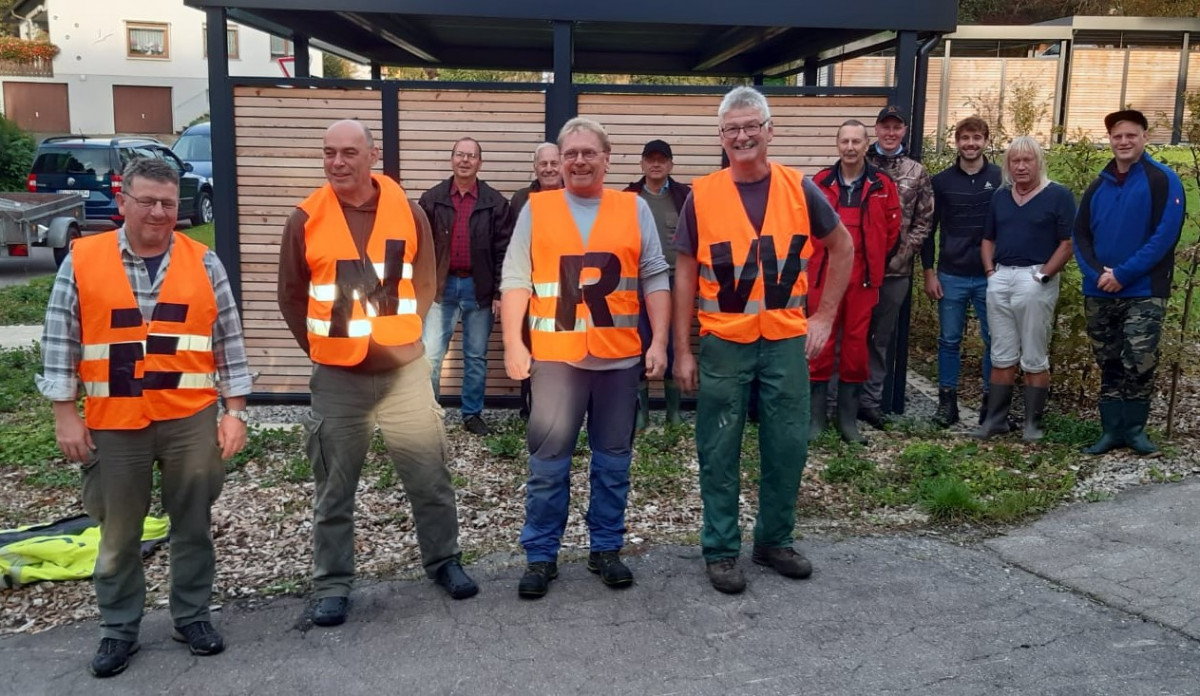 Vier Männer mit Warnwesten mit Aufschrift ENRW, dahinter weitere Männer